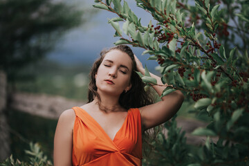 Girl in an orange dress on a background of a tree with fruits, portrait photo of a young girl