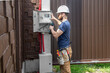 © puhimec - Electrician Builder at work, examines the cable connection in the electrical line in the fuselage of an industrial switchboard. Professional in overalls with an electrician's tool.