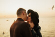 © eduard - Close up portrait of a beautiful stylish young couple in love standing and kissing on the beach at sunset. Copy space.