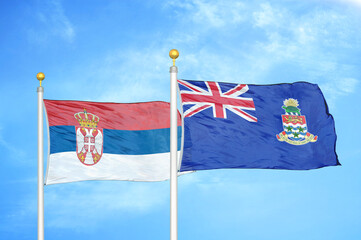 Serbia and Cayman Islands two flags on flagpoles and blue sky