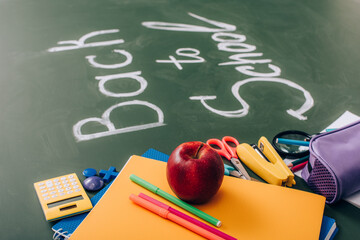 Wall Mural - selective focus of school stationery and fresh apple near back to school inscription on green chalkboard