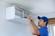 © ronstik - hvac services - technician installing air conditioner on the wall at home