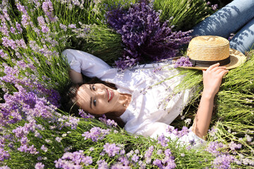 Young woman lying in lavender field on summer day