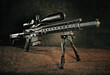 © Straight8Stock - Studio shot of an AR-15 Rifle with warm lighting, on a bipod with a silencer and optic.