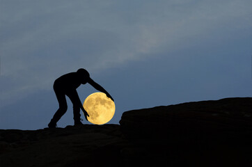 Wall Mural - A man pick up fallen full moon on rock cliff