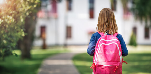 Wall Mural - Girl with rucksack infront of a school building