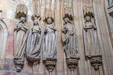 Ancient statues of young women dressed in mediaeval traditional clothes in interior of the main Catholic Cathedral in Magdeburg, Germany, details, closeup