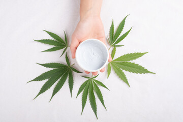 Wall Mural - Cleansing scrub in palm with marijuana plant leaf isolated on white background. beauty, skin care cosmetics