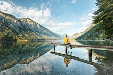 Canvas Print - Frau sitzt am See in den Bergen