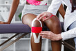 Physiotherapist applying kinesiology tape to patient knee.Therapist treating young female African American athlete. Kinesiology taping. Post traumatic rehabilitation,sport physical therapy.