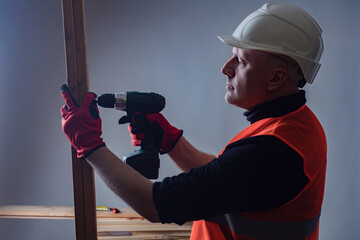 Wall Mural - Builder tightens the screw. Man works with a screwdriver. Concept - work with an electric screwdriver. Process of assembling furniture. Connection of wood elements. Concept - furniture business