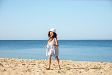 Sticker - Cute little child running at sandy beach on sunny day