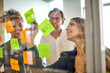© Marc Zimmermann - Smiling confident young businesswoman writing on adhesive note while discussing strategy with colleagues in board room during meeting