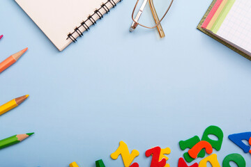 School supplies and glasses formed a frame on a light blue background. Copy space for text