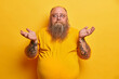 © wayhome.studio  - Indoor shot of hesitant bearded man with excess weight shrugs shoulders and stands unaware, has thick beard, big beer belly, dressed in yellow t shirt, round spectacles, faces difficult choice.