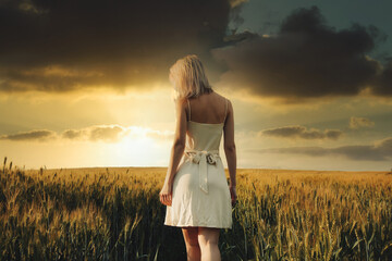 Beautiful blonde girl in wheat field in sunset time