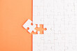 © sorapop - Top view flat lay of paper plain white jigsaw puzzle game texture last pieces for solve and place, studio shot on an orange background, quiz calculation concept
