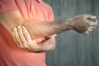 © anut21ng Stock - young man having elbow pain at arm on Cement wall background , Problems and health care concepts