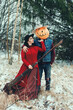 Halloween Scarecrow with a pumpkin on his head and an evil witch with a broom in her hands met in the woods