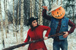 Halloween Scarecrow with a pumpkin on his head and an evil witch with a broom in her hands met in the woods