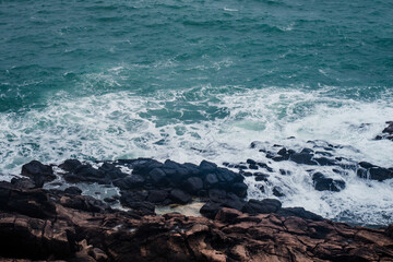Wall Mural - aerial view of crashing waves on rocks.