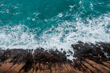 Wall Mural - aerial view of crashing waves on rocks.