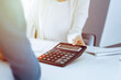 © Iryna - Accountant checking financial statement or counting by calculator income for tax form, hands close-up. Business woman sitting and working with colleague at the desk in office. Audit concept