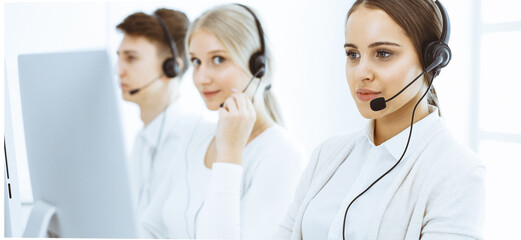 Call center. Group of diverse operators at work. Beautiful woman in headset communicating with customers of telemarketing service. Business concept