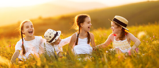 Wall Mural - happy children sit in the grass and laugh merrily in   field.