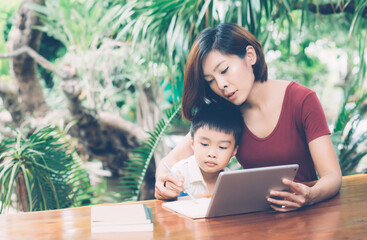 Wall Mural - Son using digital tablet computer for study and learn to internet online with mother together, education from home, family recreation, mom teach boy and homework with technology, lifestyle concept.