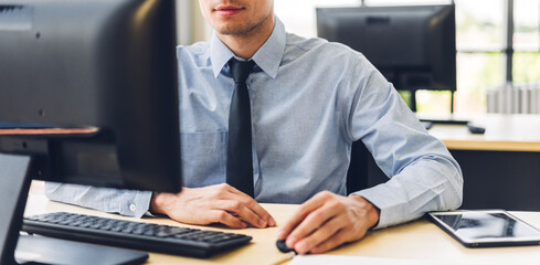 Handsome confident businessman relaxing looking at technology of desktop computer monitor while sitting on chair.Young creative coworkers business people working and typing on keyboard at office