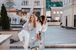 © Look! - Stylish caucasian girls dancing in front of old building. Outdoor portrait of two carefree ladies expressing good emotions and laughing.
