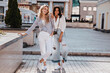 © Look! - Full-length shot of debonair fair-haired lady posing with hand in pocket. Carefree brunette girl in vintage jeans standing beside her friend.