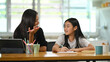 © Prathankarnpap - A young mother is teaching a daughter to do homework at the wooden table.