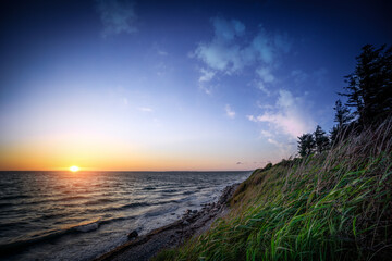 Wall Mural - sunset by the ocean coast under a blue sky