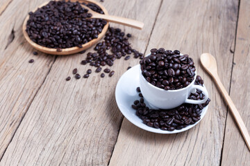 Wall Mural - Coffee beans in coffee cup on old wooden plank background.