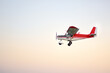 Small ultralight airplane with overhead wing and single propeller flying in sky. Such aircraft are used for recreational, sport and flight training.