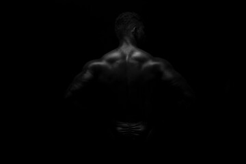 Silhouette of young athlete bodybuilder man on black