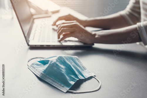 Fotomural Office worker typing on a laptop and face mask