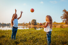 Little Girl Playing With Ball With Her Sister In Summer Park. Kids Having Fun Outdoors. Games For Children