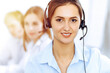 © rogerphoto - Call center operators. Focus on beautiful business woman using headset in sunny office