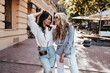 © Look! - Ecstatic tanned woman joking with friend. Outdoor portrait of pleased young ladies standing on the street.
