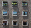 face of cement apartment building with 9 symmetrical windows in Bologna Italy