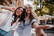 © Look! - Fascinating blonde girl making selfie on the street with friend. Stunning young ladies enjoying spring day.
