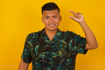 Blond European man over isolated background gesturing with hand showing small size, measure symbol. Smiling looking at the camera. Measuring concept.