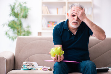 Wall Mural - Old injured man in budget planning concept