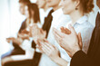 © rogerphoto - Business people clapping and applause at meeting or conference, close-up of hands. Group of unknown businessmen and women in modern white office. Success teamwork or corporate coaching concept