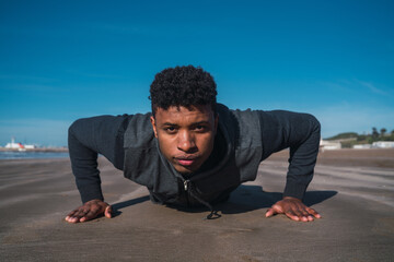 Athletic man doing push-ups at the beach.