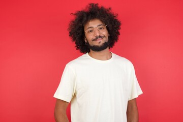 Confidence and business concept. Portrait of charming successful young man, smiling broadly with self-assured expression while holding hands in pockets standing against gray wall.