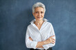 © Anatoliy Karlyuk - Isolated image of stylish successful 50 year old female broker in white shirt posing against blank studio wall background, crossing arms on her chest, having confident facial expression, smiling